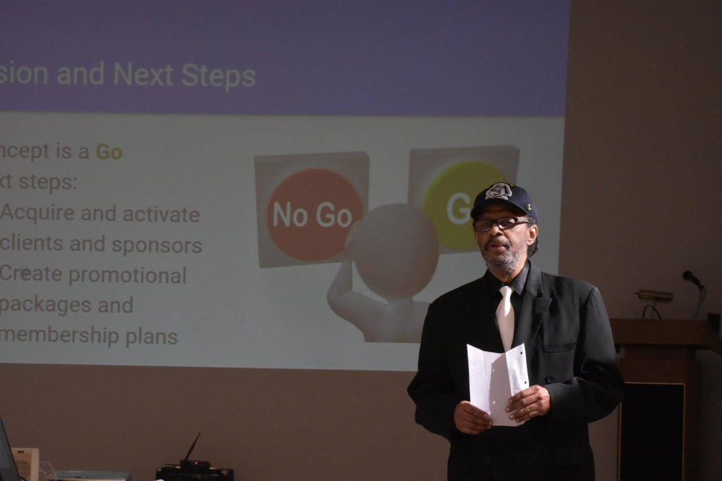 Man wearing a dark suit and a ECU hat, holds a piece of paper and talks about his "Go" or "No-Go" decision