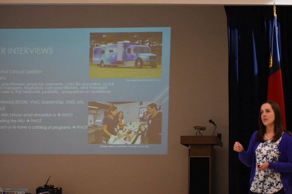 student talks in front of a screen showing a clinical simulation truck